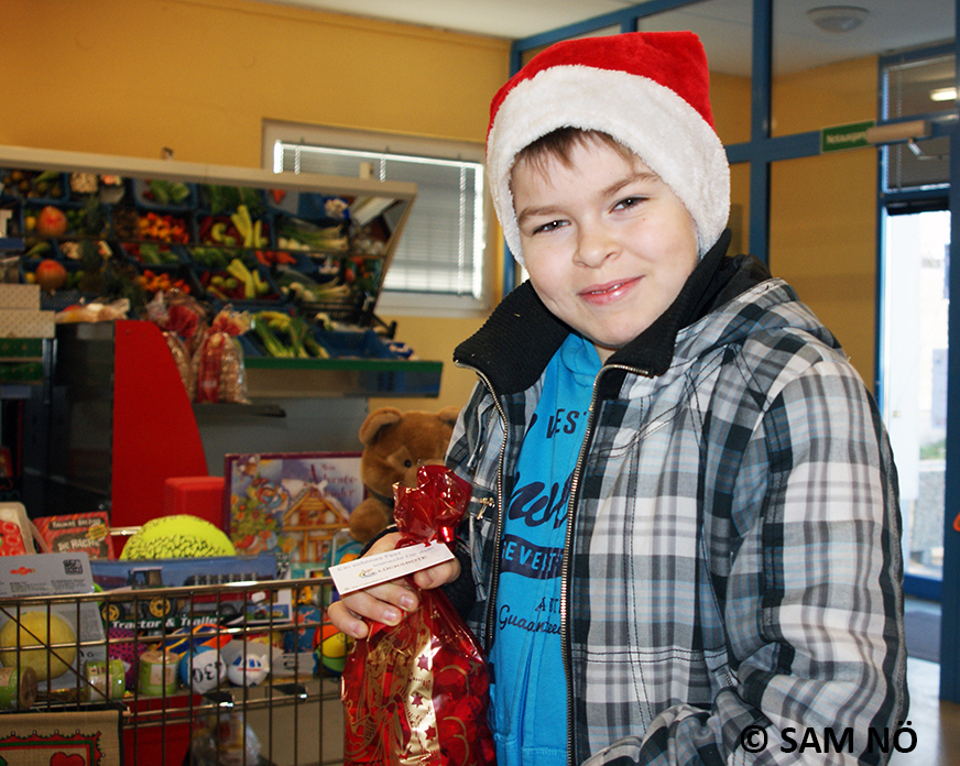 Kind mit Weihnachtsmütze und Geschenkesackerl