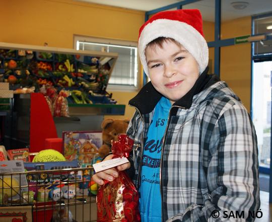 Kind mit Weihnachtsmütze und Geschenkesackerl