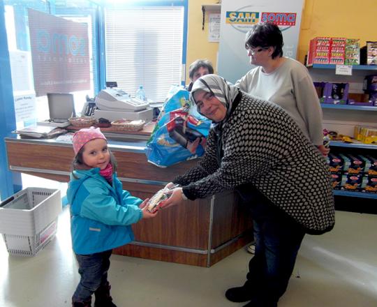 Nazife Menekse, die Marktleiterin, überreicht einem Kind ein Ostersackerl